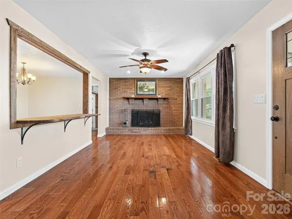 a view of an empty room with window wooden floor and a kitchen