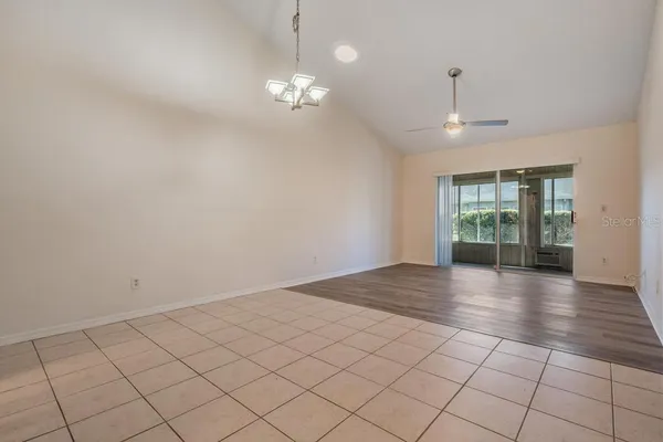 an empty room with wooden floor chandelier and windows