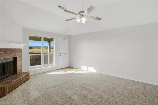 a view of an empty room with a fireplace and a window