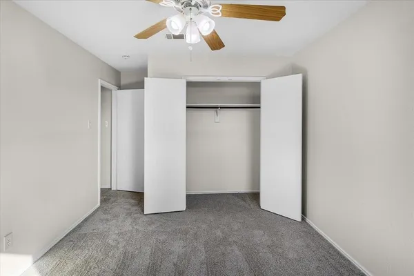 an empty room with closet and a chandelier fan