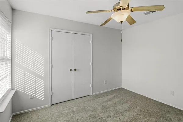 an empty room with windows and fan