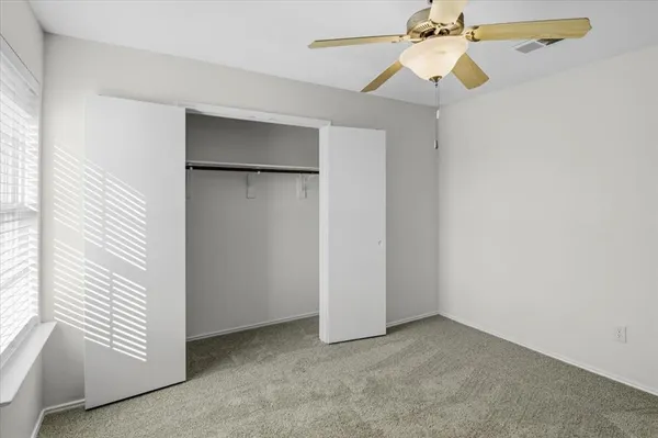 an empty room with a ceiling fan and a window