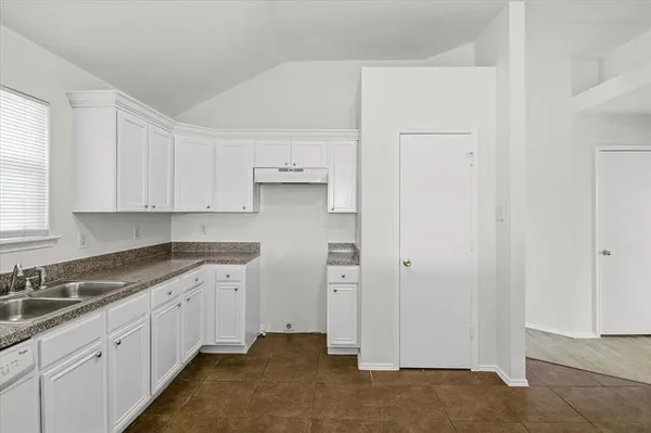a kitchen with granite countertop white cabinets and sink