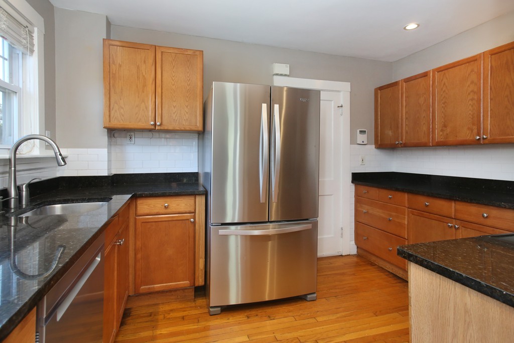 a kitchen with granite countertop stainless steel appliances a refrigerator sink and cabinets