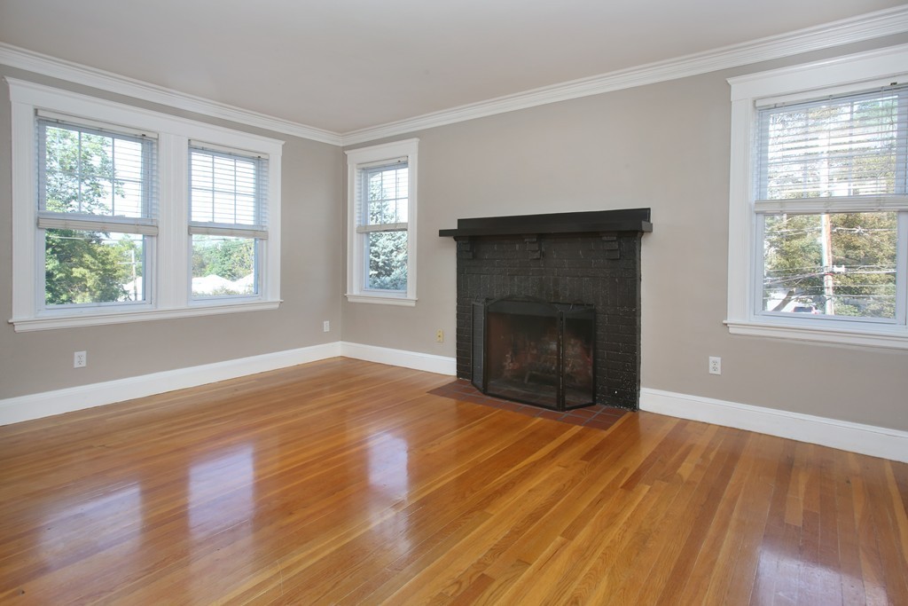 199-201 Langley Road, Unit 201 Newton, MA 02459 - Photo 3 of 5 an empty room with wooden floor fireplace and windows