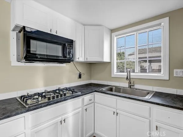 a kitchen with granite countertop a sink a stove and cabinets