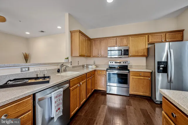 a kitchen with stainless steel appliances a stove a sink a refrigerator and a microwave