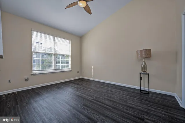 an empty room with wooden floor fan and windows