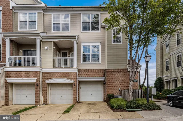 a front view of a residential apartment building with a yard and garage