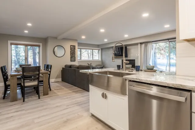 a kitchen with stainless steel appliances granite countertop wooden cabinets a sink a stove a dining table and chairs