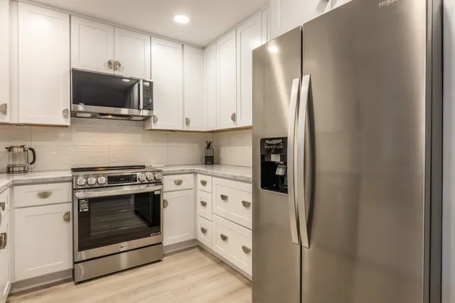 a kitchen with stainless steel appliances white cabinets and a stove top oven