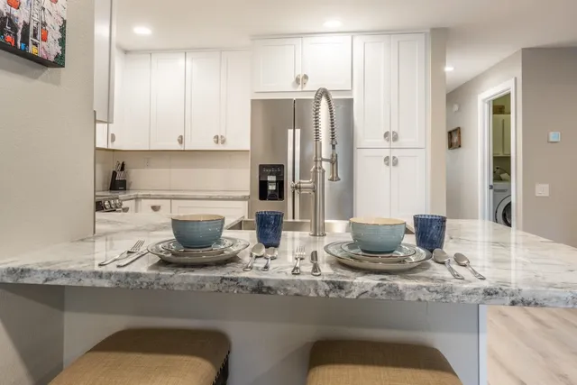 a kitchen with granite countertop a refrigerator and cabinets