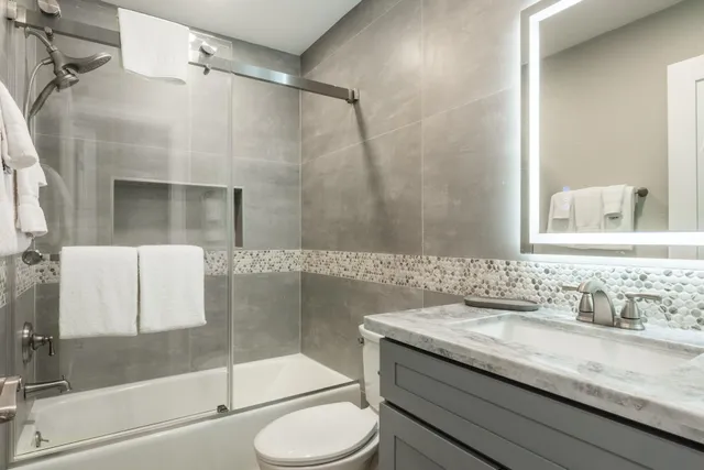 a bathroom with a granite countertop sink toilet and shower