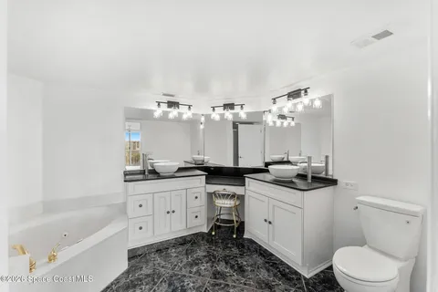 a bathroom with a double vanity sink a toilet a mirror and bathtub