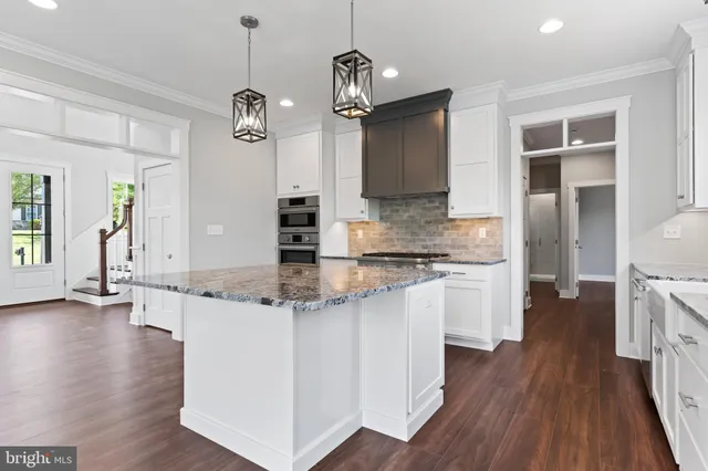 a kitchen with stainless steel appliances granite countertop wooden floors and white cabinets