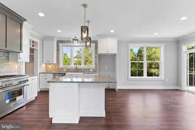 a large kitchen with granite countertop a stove a sink dishwasher a refrigerator and wooden floor