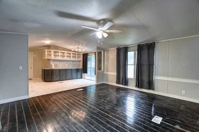 a view of an empty room with window and wooden floor