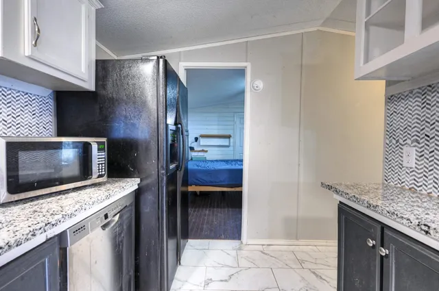 a kitchen with stainless steel appliances kitchen island granite countertop a stove a microwave and a sink