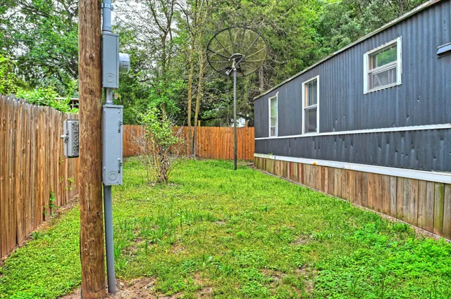 a view of backyard with large trees and wooden fence