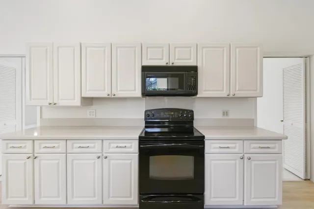 a view of a kitchen with kitchen island stainless steel appliances wooden floor dining table and chairs