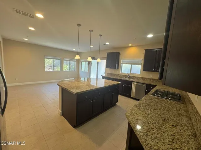 a kitchen with stainless steel appliances granite countertop a sink a stove and a wooden floors