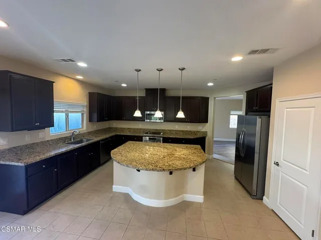 a large kitchen with a large counter top stainless steel appliances and cabinets