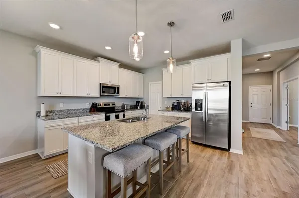 a kitchen with granite countertop a refrigerator a stove a sink dishwasher a oven with wooden floor and cabinets