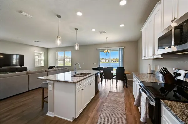 a kitchen with stainless steel appliances kitchen island granite countertop a sink a stove and a wooden floors