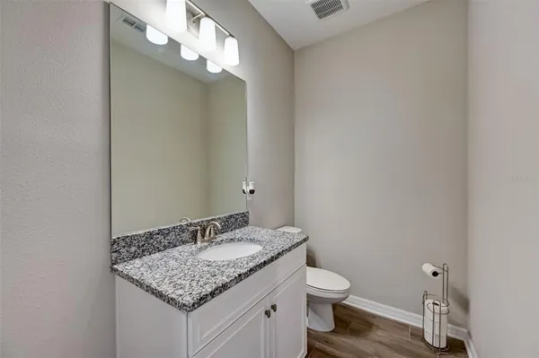 a bathroom with a granite countertop sink toilet and a mirror