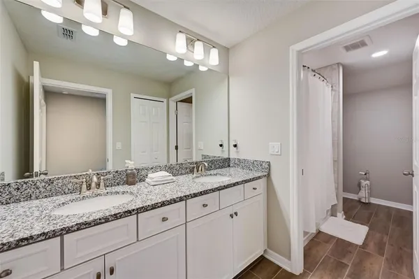 a bathroom with a granite countertop double vanity sink and mirror