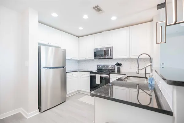 a kitchen with a refrigerator sink and white cabinets