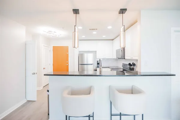 a kitchen with stainless steel appliances kitchen island a sink a refrigerator and cabinets
