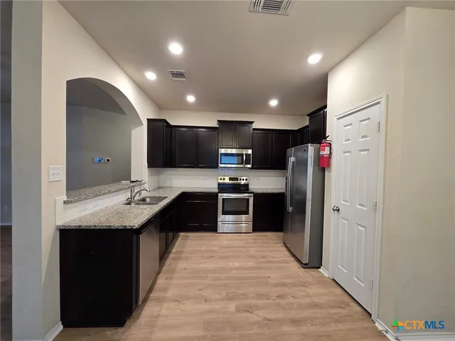 a kitchen with stainless steel appliances granite countertop a refrigerator a sink and a stove