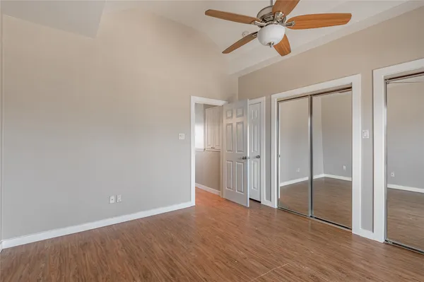 an empty room with wooden floor closet and fan