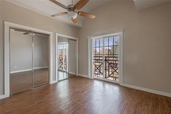 an empty room with wooden floor closet and windows