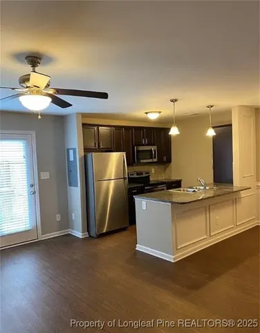 a view of kitchen with stainless steel appliances wooden floor and living room view