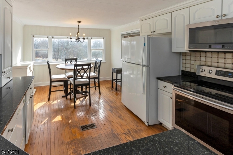 195 West Main Street, Unit G Chester, NJ 07930 - Photo 11 of 23 a kitchen with stainless steel appliances granite countertop a stove refrigerator and a dining table with wooden floor