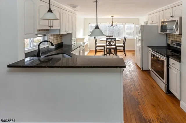 a kitchen with stainless steel appliances granite countertop a stove refrigerator and a dining table with wooden floor