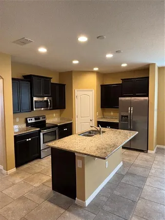 a kitchen with granite countertop a stove top oven and refrigerator