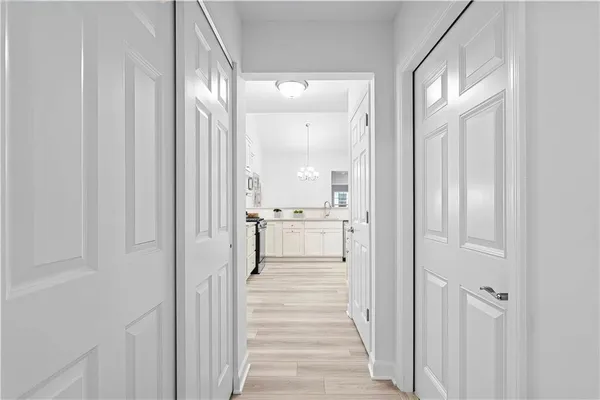 a view of a hallway with wooden floor cabinets and a kitchen