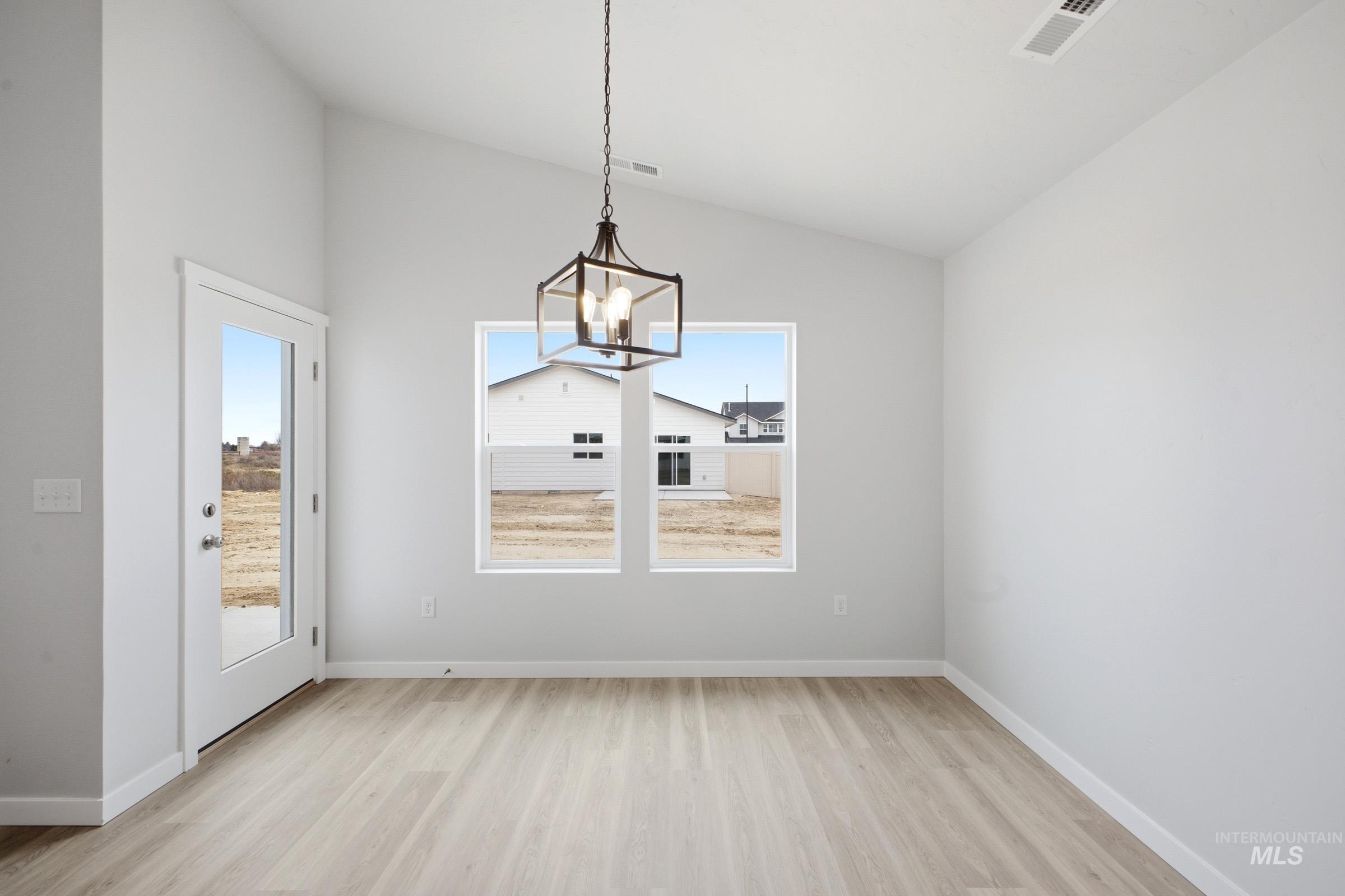 1598 Sunday River Street Middleton, ID 83644 - Photo 6 of 17 Vaulted ceiling interior with a contemporary chandelier, two large windows, wood-finish flooring, and a glass-paneled door