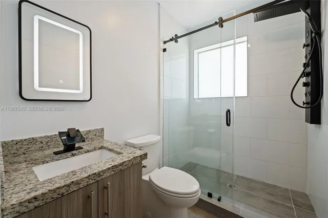 a bathroom with a granite countertop toilet sink and mirror