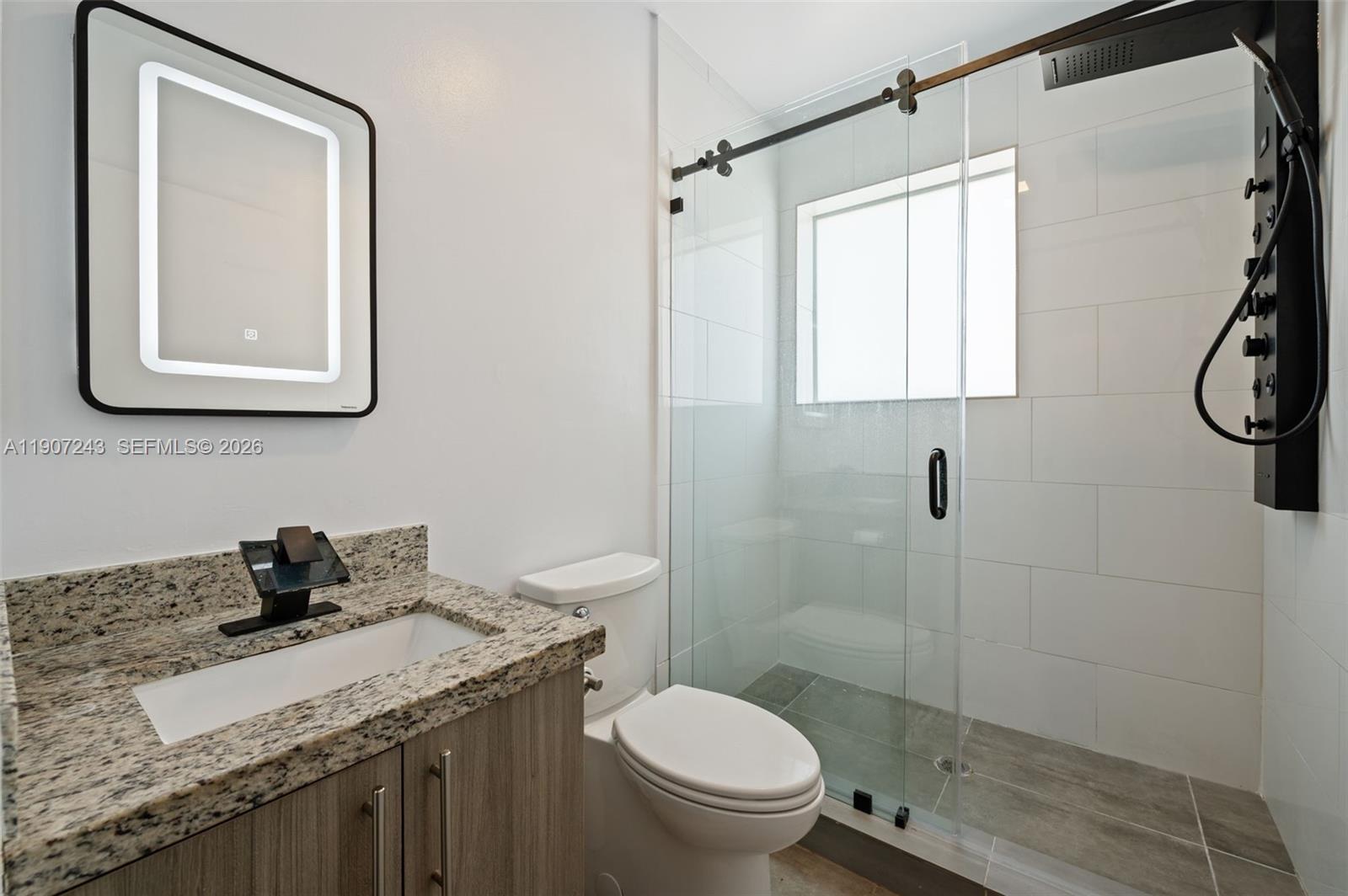 165 Northwest 39th Street, Unit 7 Miami, FL 33127 - Photo 12 of 19 a bathroom with a granite countertop toilet sink and mirror