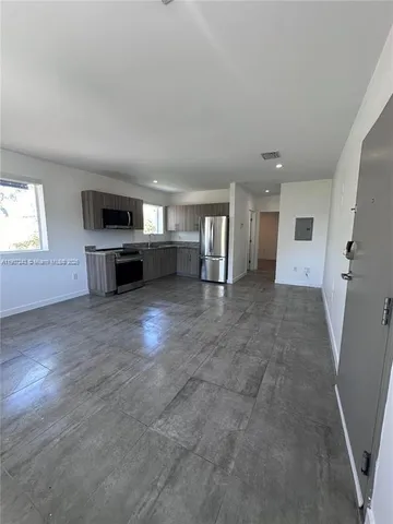 an empty room with a kitchen and a window