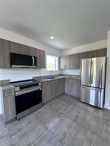 a kitchen with stainless steel appliances granite countertop a stove a sink and a refrigerator