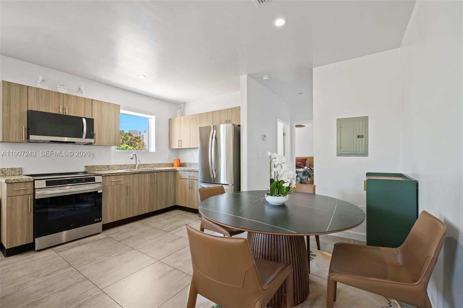 165 Northwest 39th Street, Unit 7 Miami, FL 33127 - Photo 6 of 19 a kitchen with a table chairs microwave and refrigerator