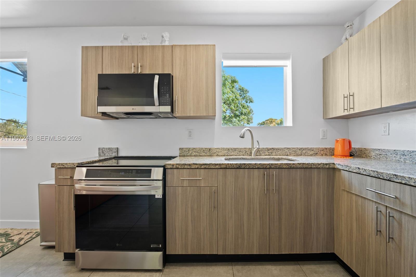165 Northwest 39th Street, Unit 7 Miami, FL 33127 - Photo 9 of 19 a kitchen with stainless steel appliances a stove a microwave sink and cabinets