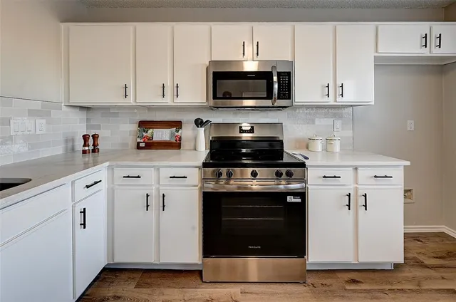 a kitchen with white cabinets and stainless steel appliances