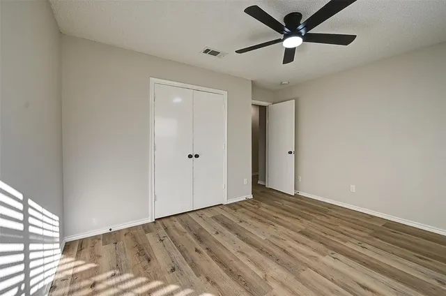 a view of a big room with wooden floor and a ceiling fan