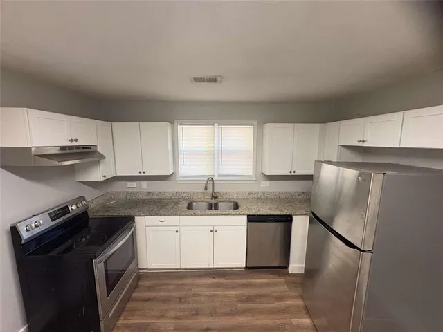 a kitchen with a sink a stove a refrigerator and cabinets